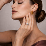 Woman wearing a gold earring and ring, with a neutral background at LeGassick Gold Coast.