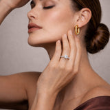 Woman wearing a gold earring and ring, with a neutral background at LeGassick Gold Coast.