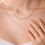 Gold necklace on a person's neck with a neutral background