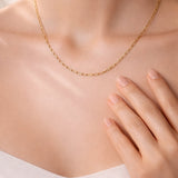 Gold necklace on a person's neck with a neutral background