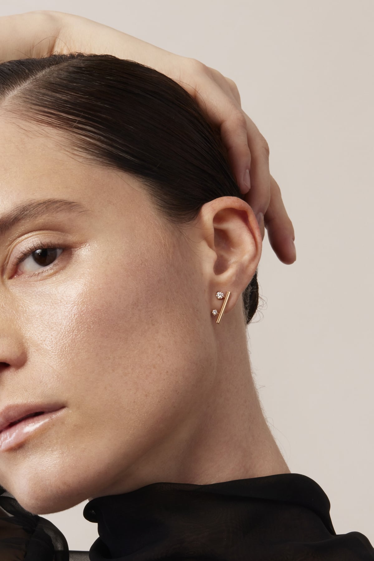 Close-up of a woman wearing a gold earring with a beige background