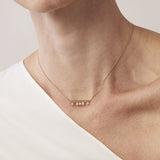 Necklace with small beads on a person wearing a white top against a neutral background