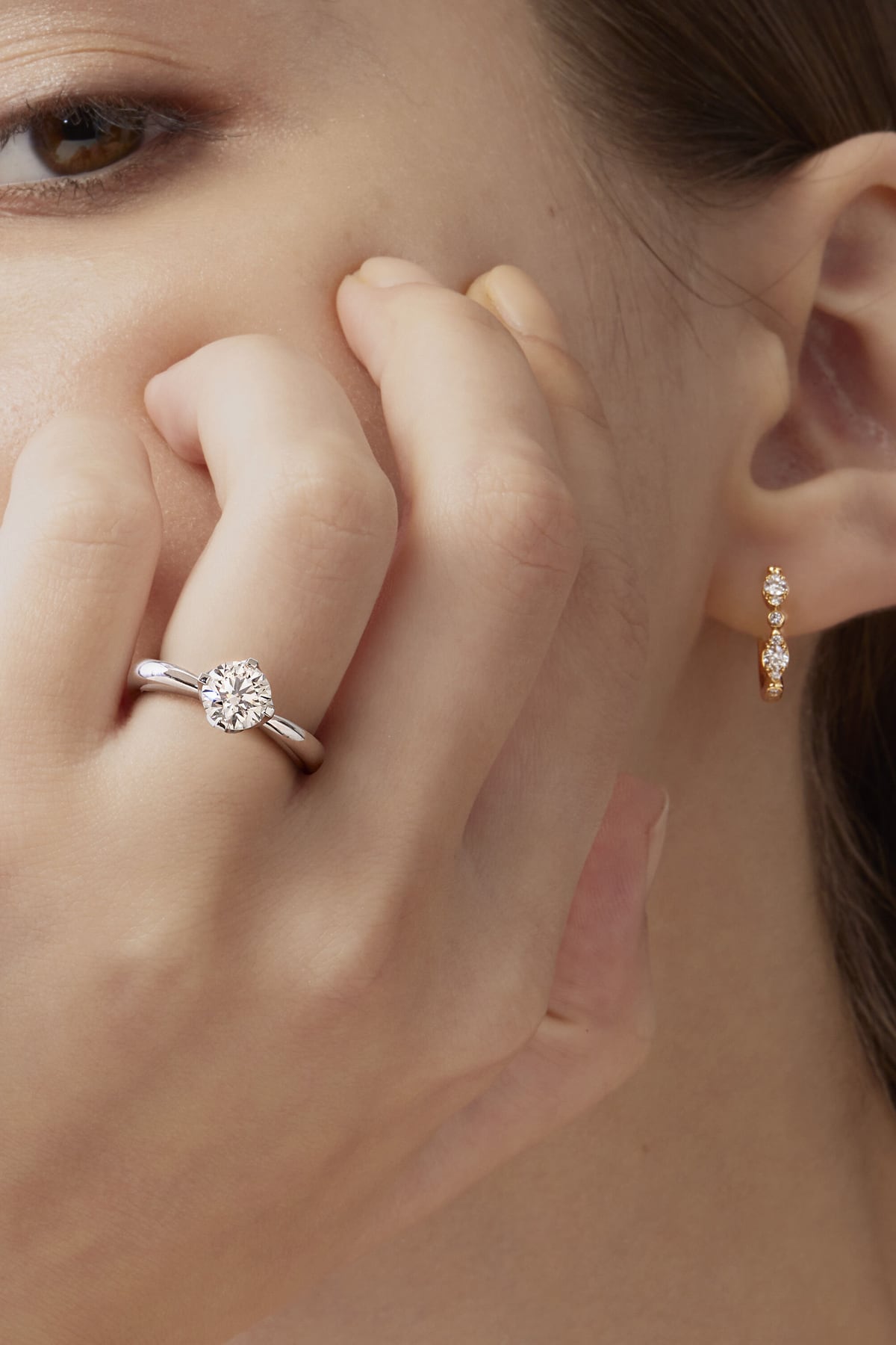 Close-up of a woman wearing a silver ring and gold earrings.