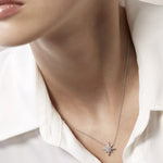 Close-up of a diamond necklace and earring set worn by a person in a white shirt.