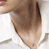 Close-up of a diamond necklace and earring set worn by a person in a white shirt.