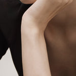 Rose gold bracelet on a person's wrist with a neutral background