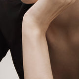 Rose gold bracelet on a person's wrist with a neutral background