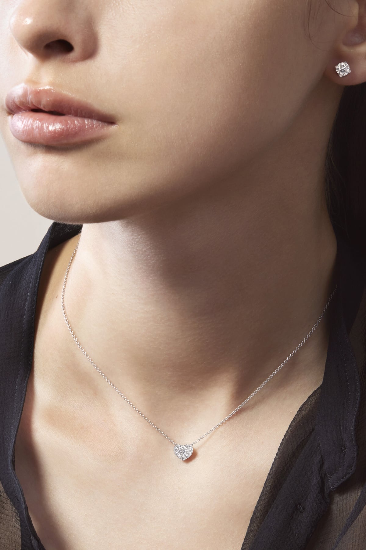 Close-up of a woman wearing a heart-shaped diamond necklace and earrings.