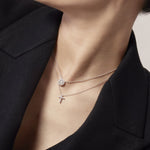 Close-up of a person wearing two necklaces with pendants.