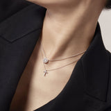 Close-up of a person wearing two necklaces with pendants.