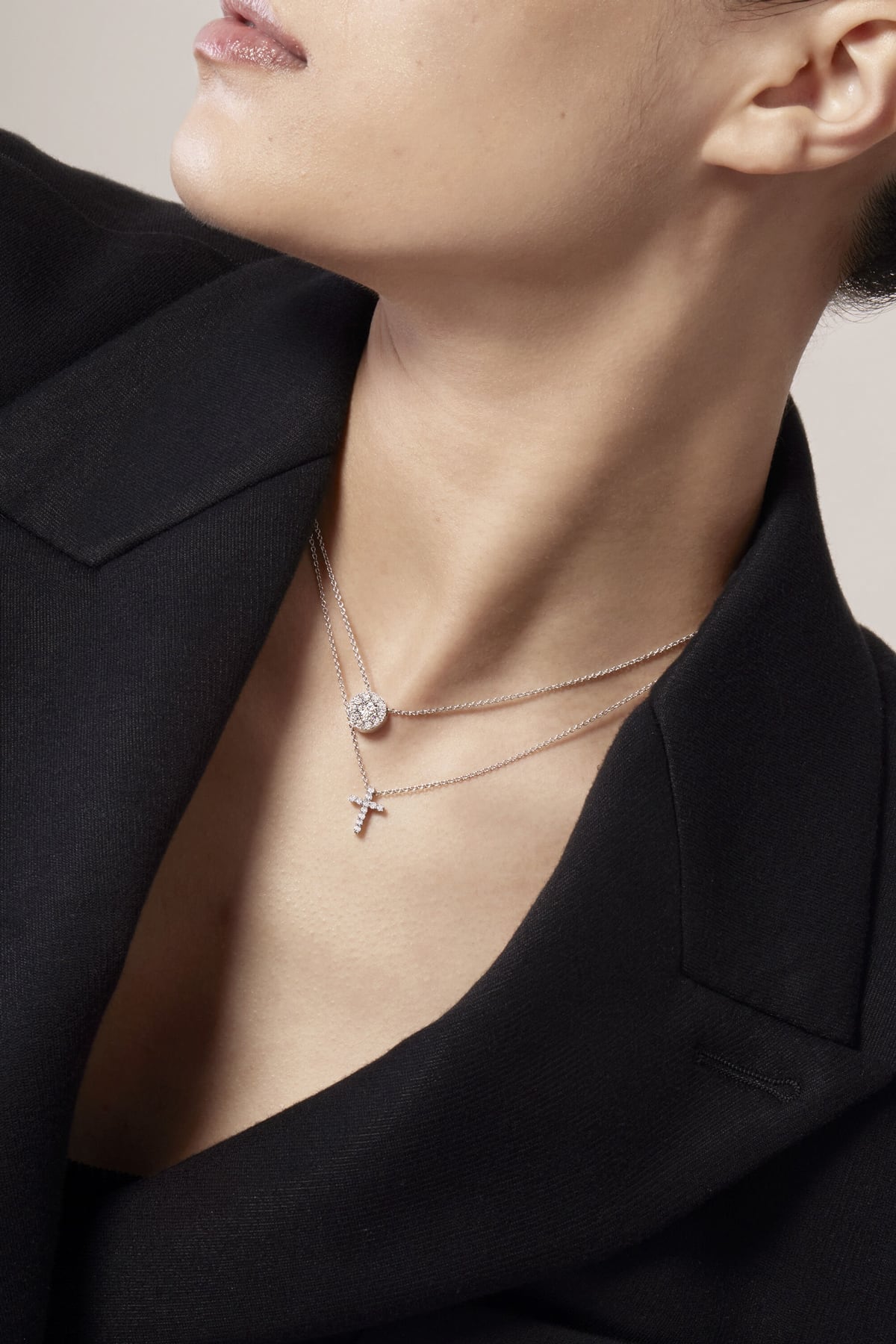 Close-up of a person wearing two necklaces with pendants.