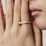 Close-up of a hand wearing a gold ring with a beige background