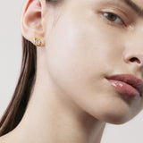 Close-up of a woman wearing a gold earring with a diamond on a neutral background