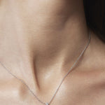 Silver cross necklace on a person's neck