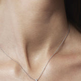 Silver cross necklace on a person's neck