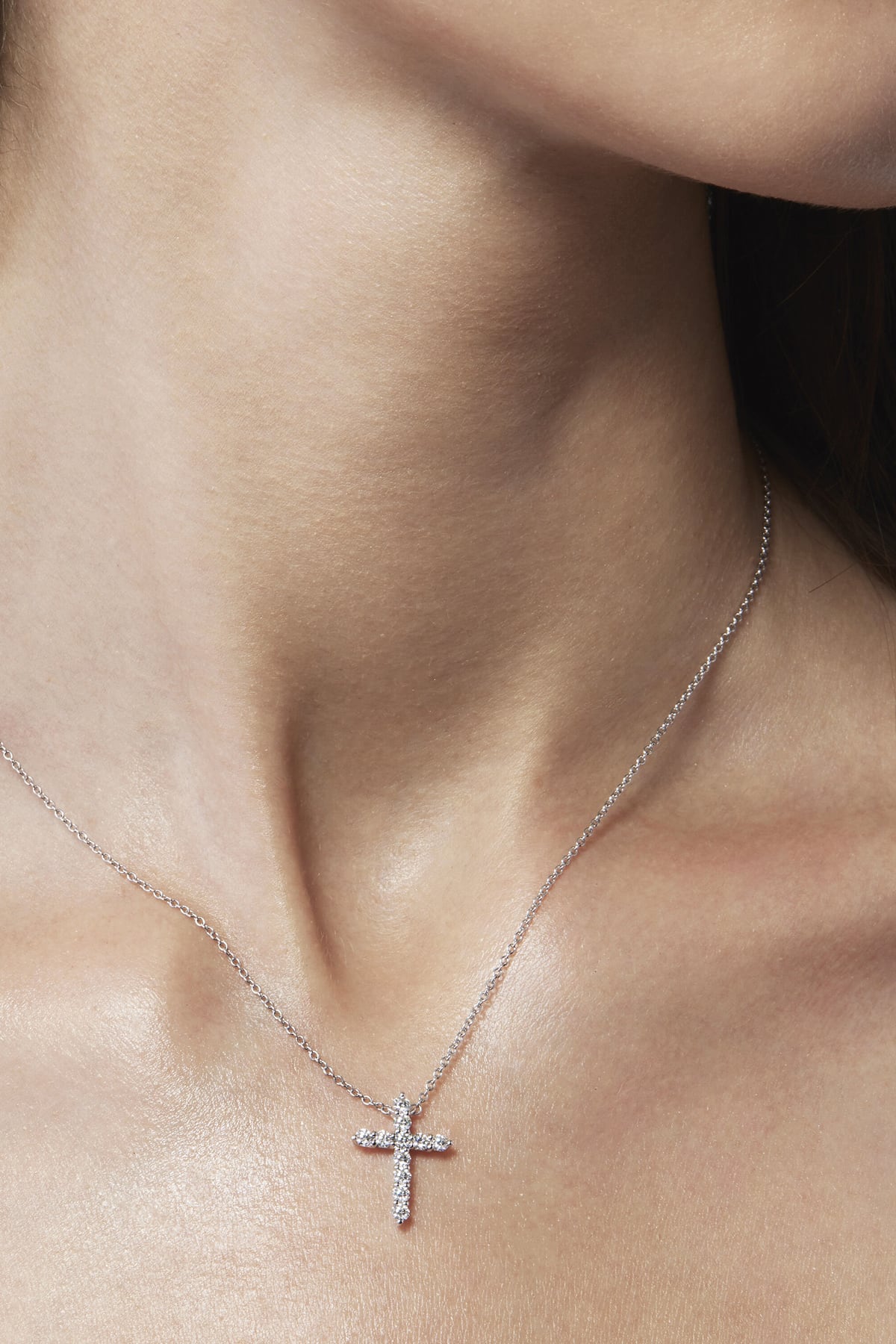 Silver cross necklace on a person's neck