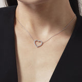 Necklace with a heart-shaped pendant worn by a person against a black background