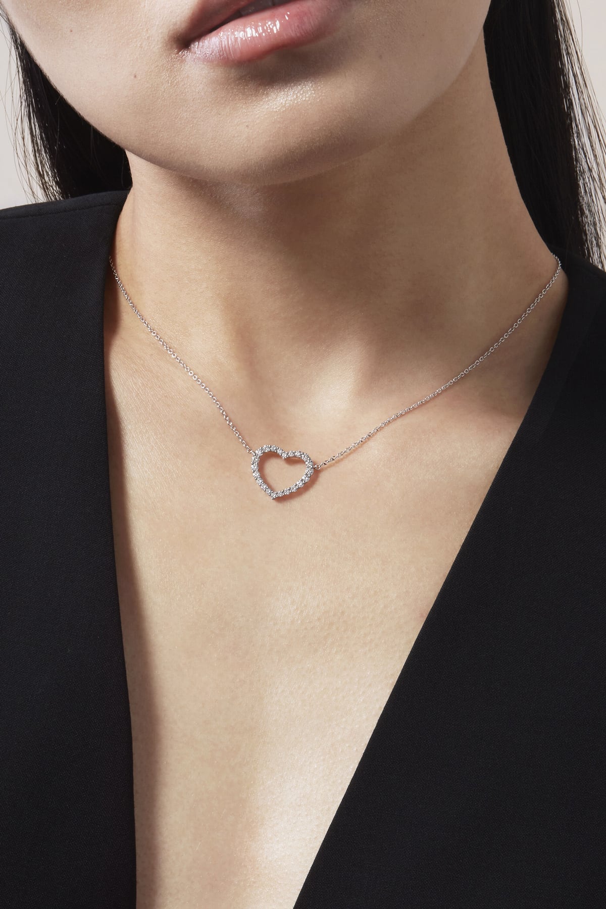 Necklace with a heart-shaped pendant worn by a person against a black background