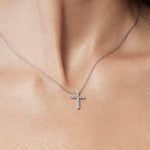 Silver cross necklace on a person's neck