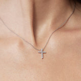 Silver cross necklace on a person's neck