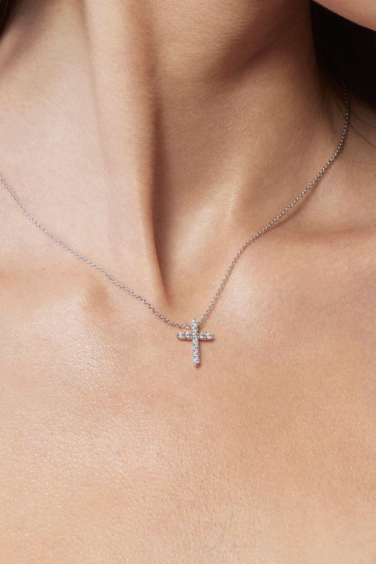 Silver cross necklace on a person's neck