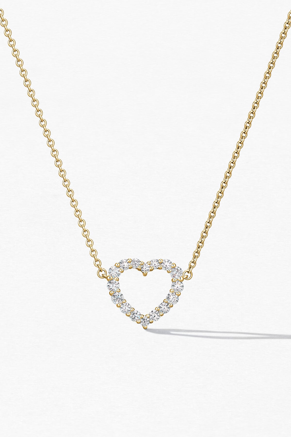 Gold necklace with a heart-shaped diamond pendant on a white background