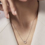 Necklace with a circular pendant worn by a person against a neutral background