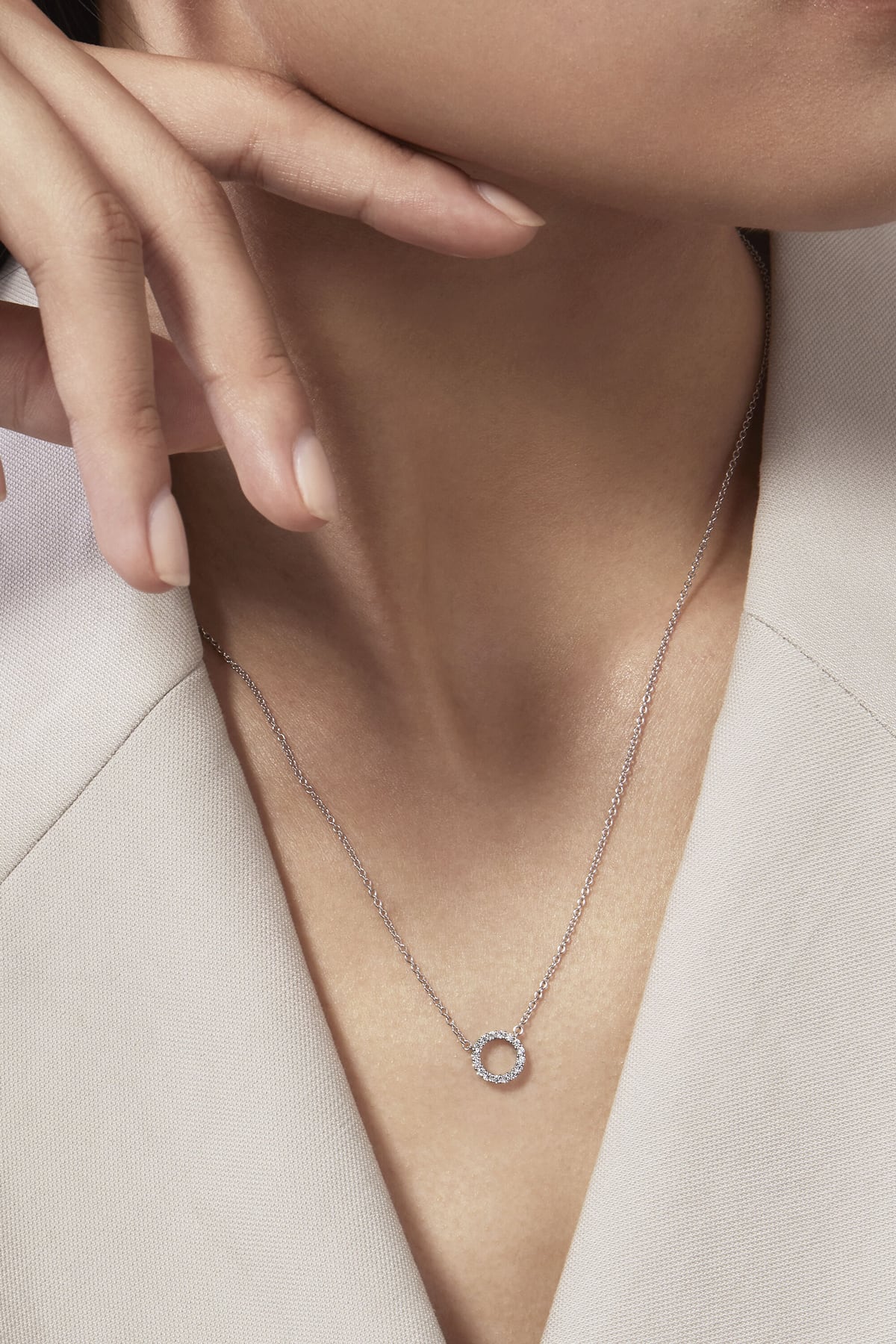 Necklace with a circular pendant worn by a person against a neutral background