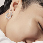 Close-up of a person wearing a silver earring with a neutral background