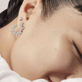 Close-up of a person wearing a silver earring with a neutral background