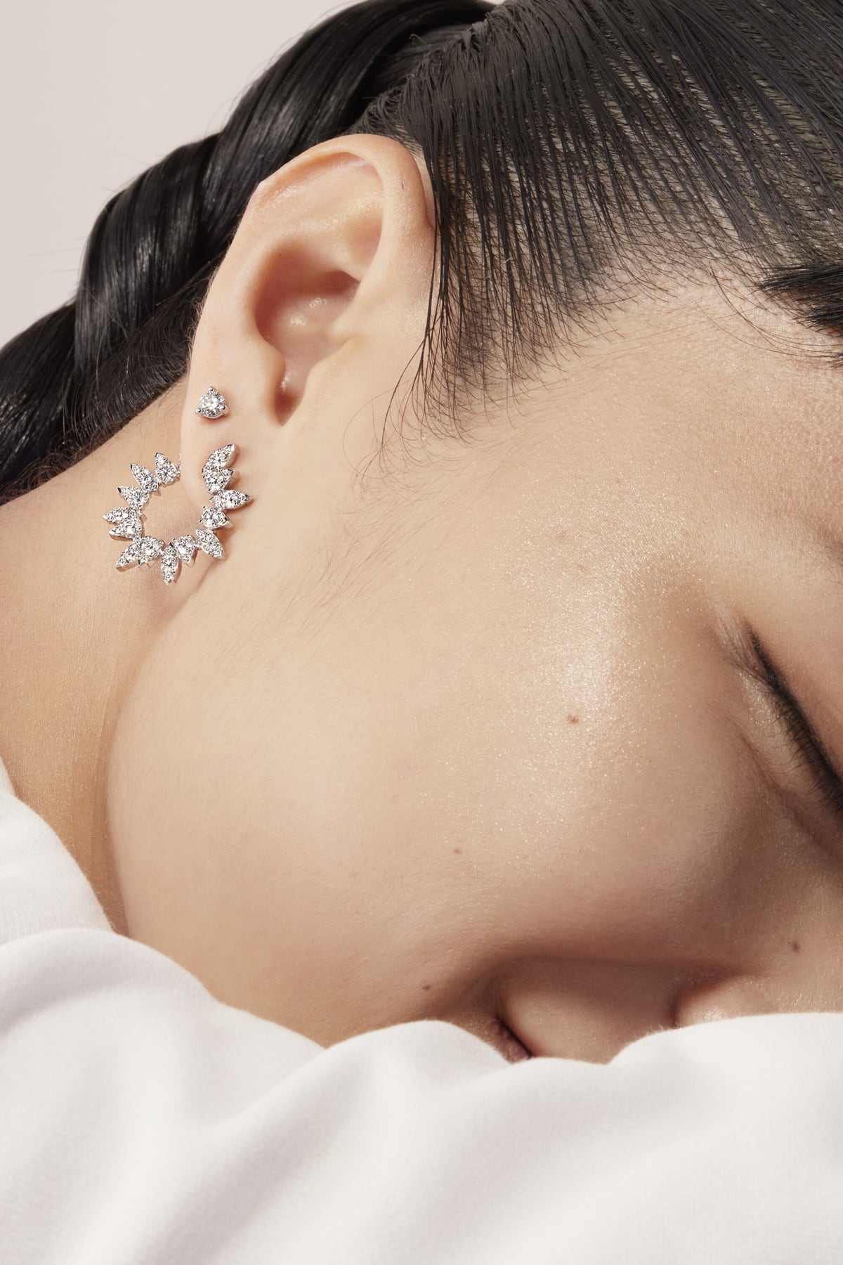 Close-up of a person wearing a silver earring with a neutral background