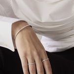 Close-up of a hand wearing two silver rings with a white shirt background