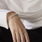 Close-up of a hand wearing two silver rings with a white shirt background