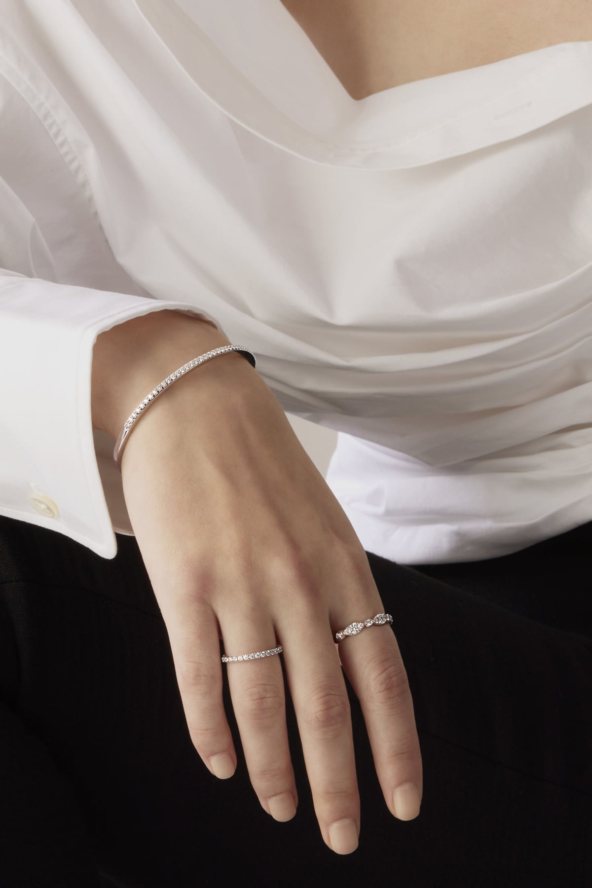 Close-up of a hand wearing two silver rings with a white shirt background