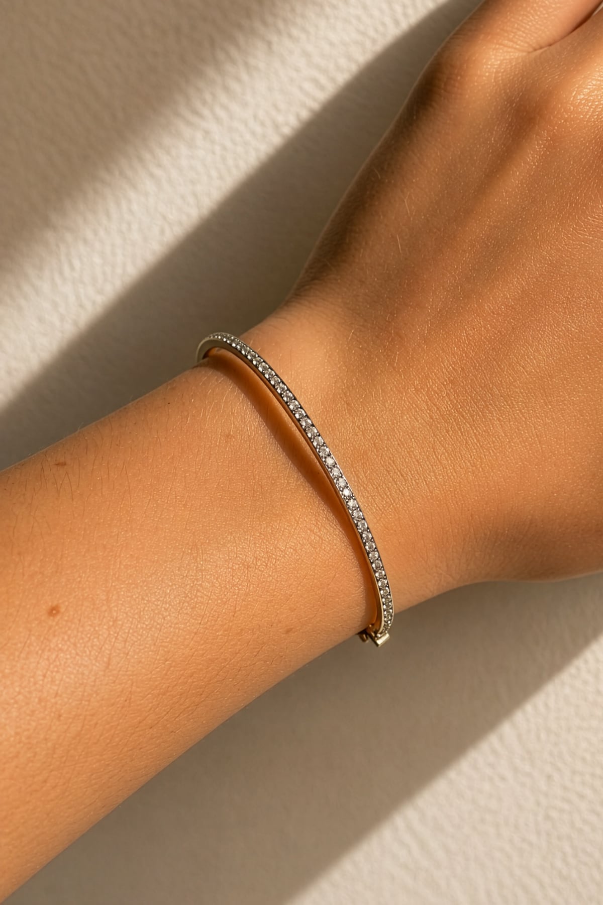 White Gold diamond bracelet on a wrist against a neutral background