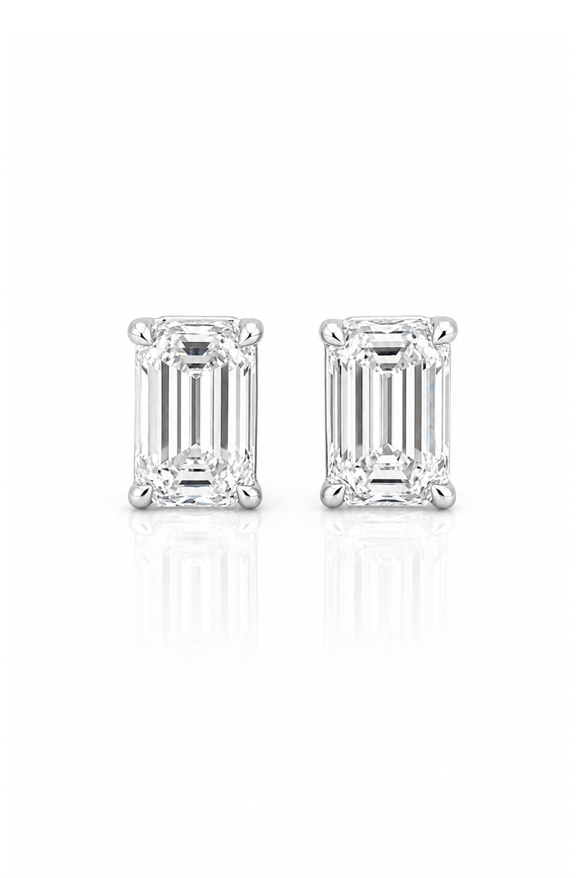 A pair of emerald-cut diamond stud earrings in a white gold setting, displayed on a clean white background with a soft reflection below.