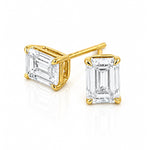 A pair of yellow gold stud earrings featuring rectangular emerald-cut clear diamonds in four-prong settings, shown on a clean white background.