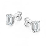 A pair of white gold stud earrings featuring rectangular emerald-cut clear diamonds in four-prong settings, shown on a clean white background.