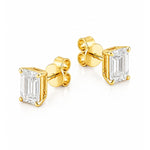 A pair of yellow gold stud earrings featuring rectangular emerald-cut clear diamonds in four-prong settings, shown on a clean white background.