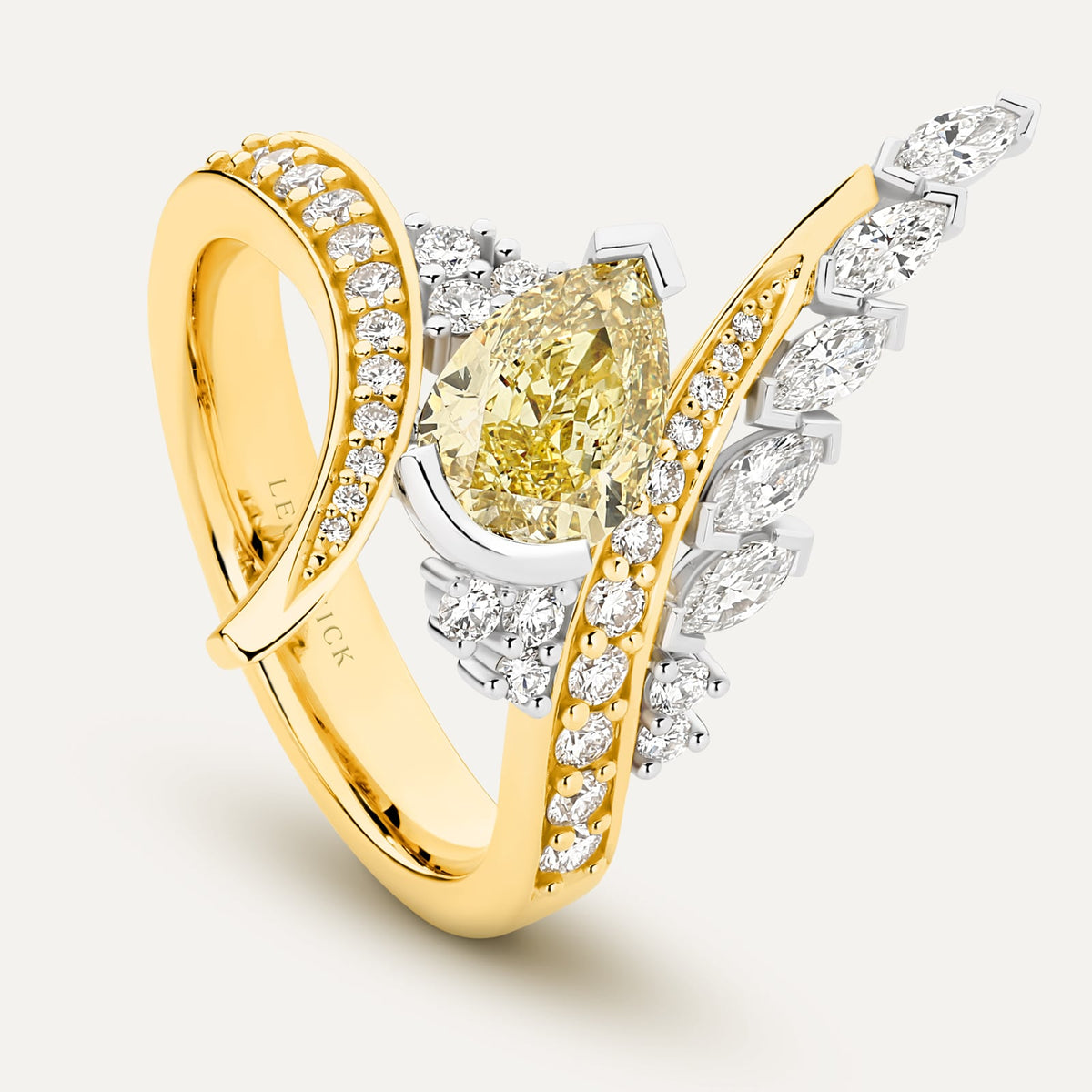 A luxury yellow gold and white gold ring featuring a pear-cut yellow diamond centre stone and multiple round and marquise-cut clear diamonds, shown on a light cream background.