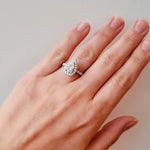 Diamond ring with a pear-shaped centre stone and diamond halo on a lady's hand