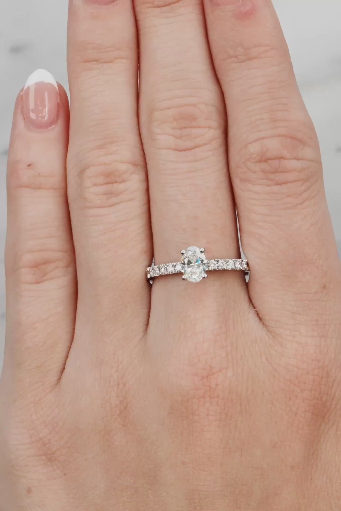 Hand wearing a silver ring with a diamond on a light grey background at LeGassick.