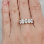 Silver ring with five diamonds on a hand with light pink nail polish against a light grey background at LeGassick.