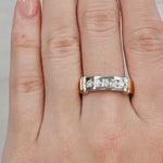 Hand wearing a gold and silver ring on a neutral background at LeGassick.