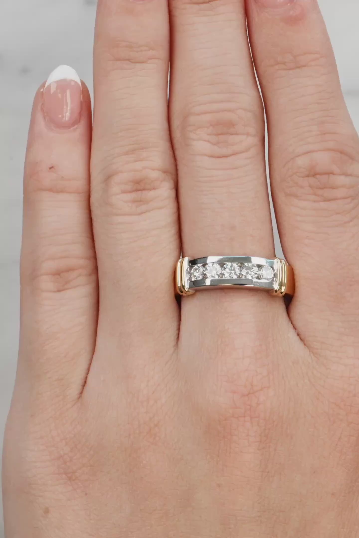 Hand wearing a gold and silver ring on a neutral background at LeGassick.
