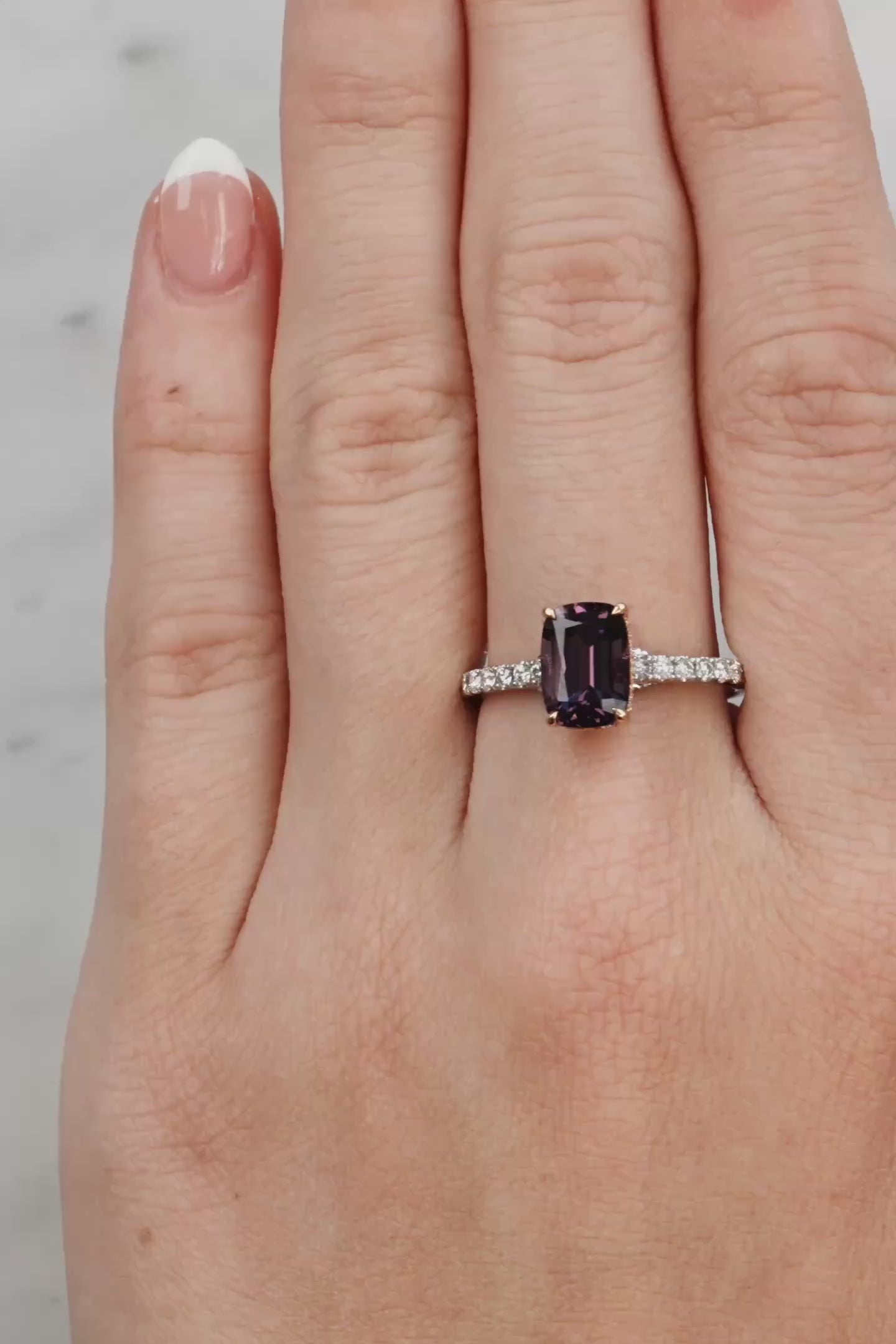 Hand wearing a ring with a purple gemstone on a light background at LeGassick Showroom.