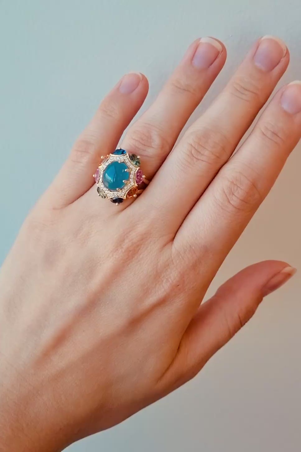 Ring with a blue gemstone on a hand against a brown background