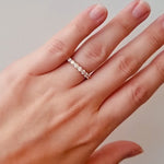 Hand wearing a rose gold diamond ring on a neutral background