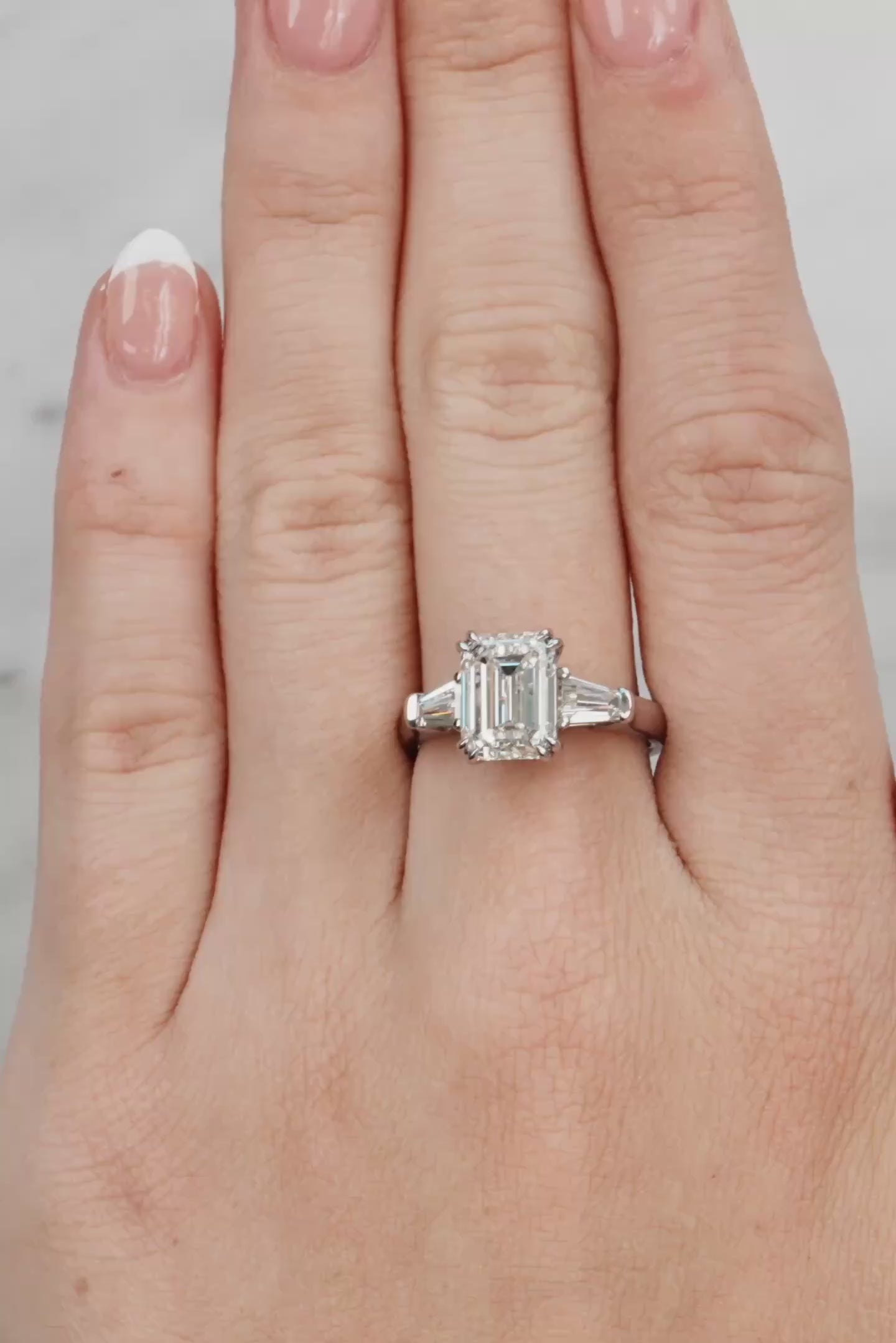 Hand wearing a diamond ring with a light grey background at LeGassick.
