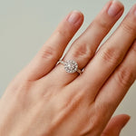 Hand wearing a diamond ring on a neutral background